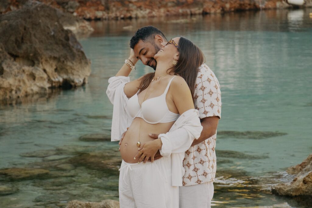 Photographe francophone à Minorque, je capture vos souvenirs de grossesse face à la mer turquoise d'Es Canutells. Séance naturelle et authentique, devis gratuit sous 48h.